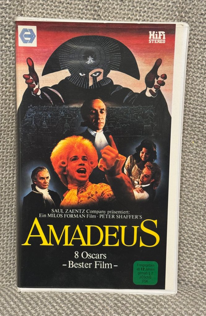 Cover eines Filmes namens 'Amadeus', mit den Hauptfiguren und dem Titel, der 8 Oscars als bester Film auszeichnet.