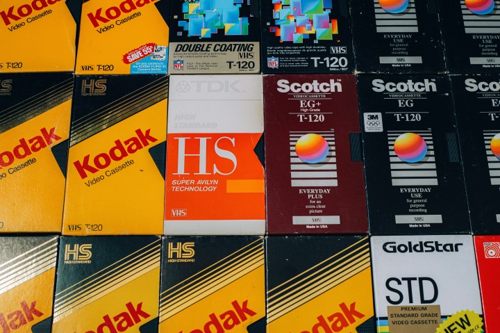 Eine Ansammlung von VHS-Kassettenboxen verschiedener Marken wie Kodak, TDK, Scotch und GoldStar, die mit unterschiedlichen Designs und Beschriftungen gestaltet sind.