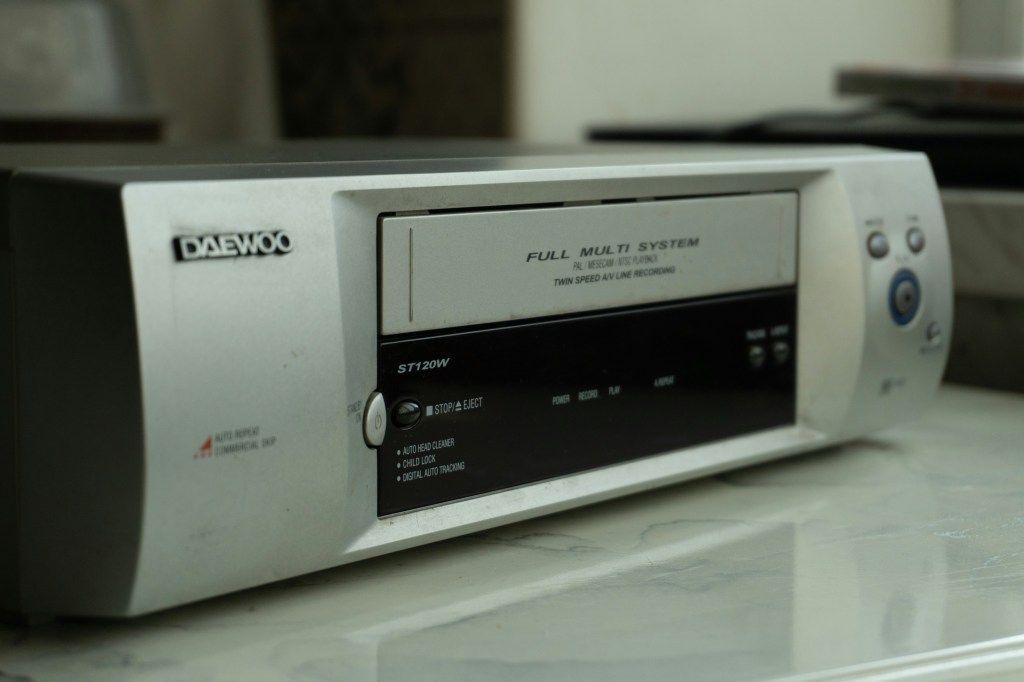 Daewoo VHS-Recorder Modell ST120W auf einem Tisch, mit Funktionen wie Auto-Head-Cleaner und Kindersicherung.